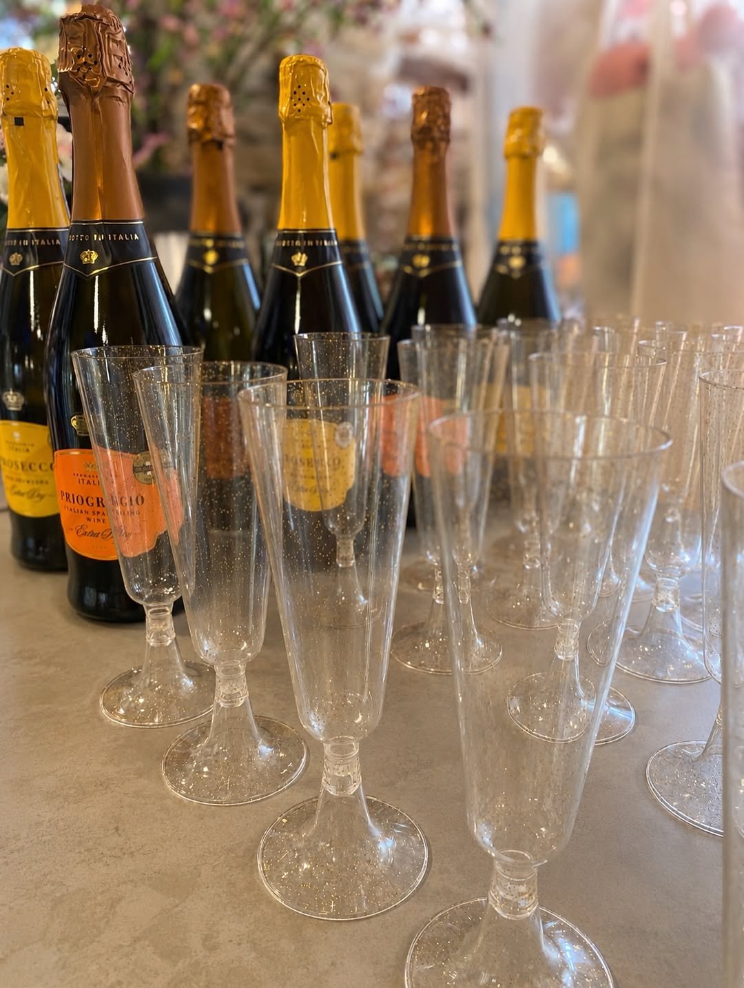 Bottles of prosecco and glitter champagne flutes set out on a stone counter inside the shop, ready for the anniversary weekend.